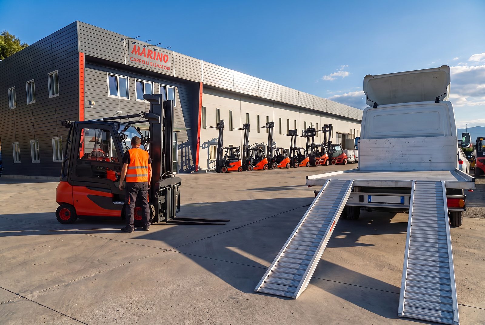 Un carrello elevatore pronto da caricare sul camion con pianale e rampe, davanti alla sede di Marino Carrelli a Beinette
